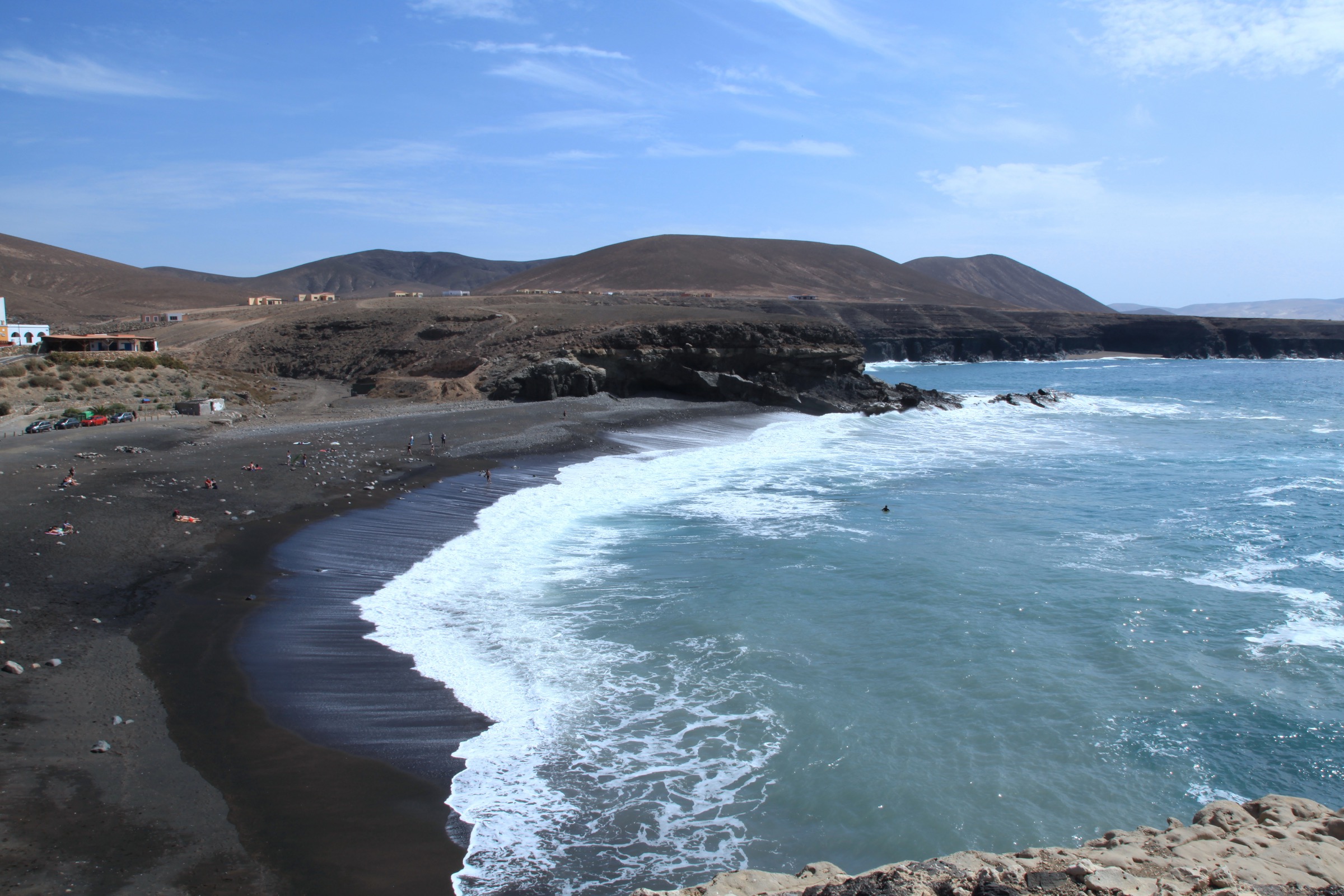 The black volcanic sand beach at Ajuy with dark hills rising behind