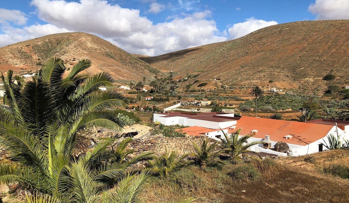 The village of Betancuria nestled in a green mountain valley with palm trees and whitewashed buildings