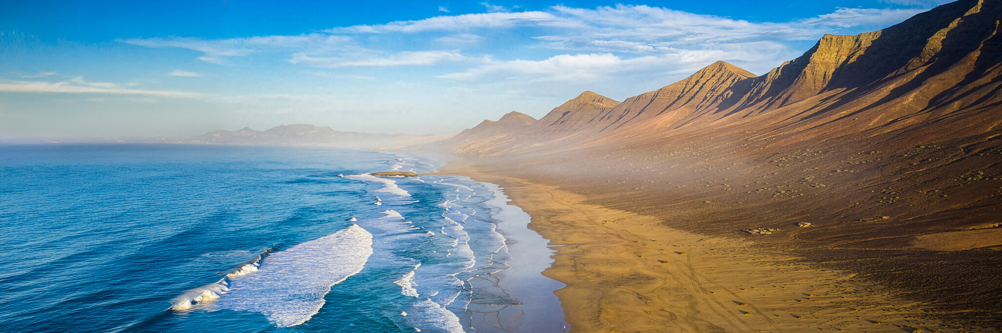 Panoramic view of Cofete Beach with the Jandía mountains rising behind an endless stretch of golden sand