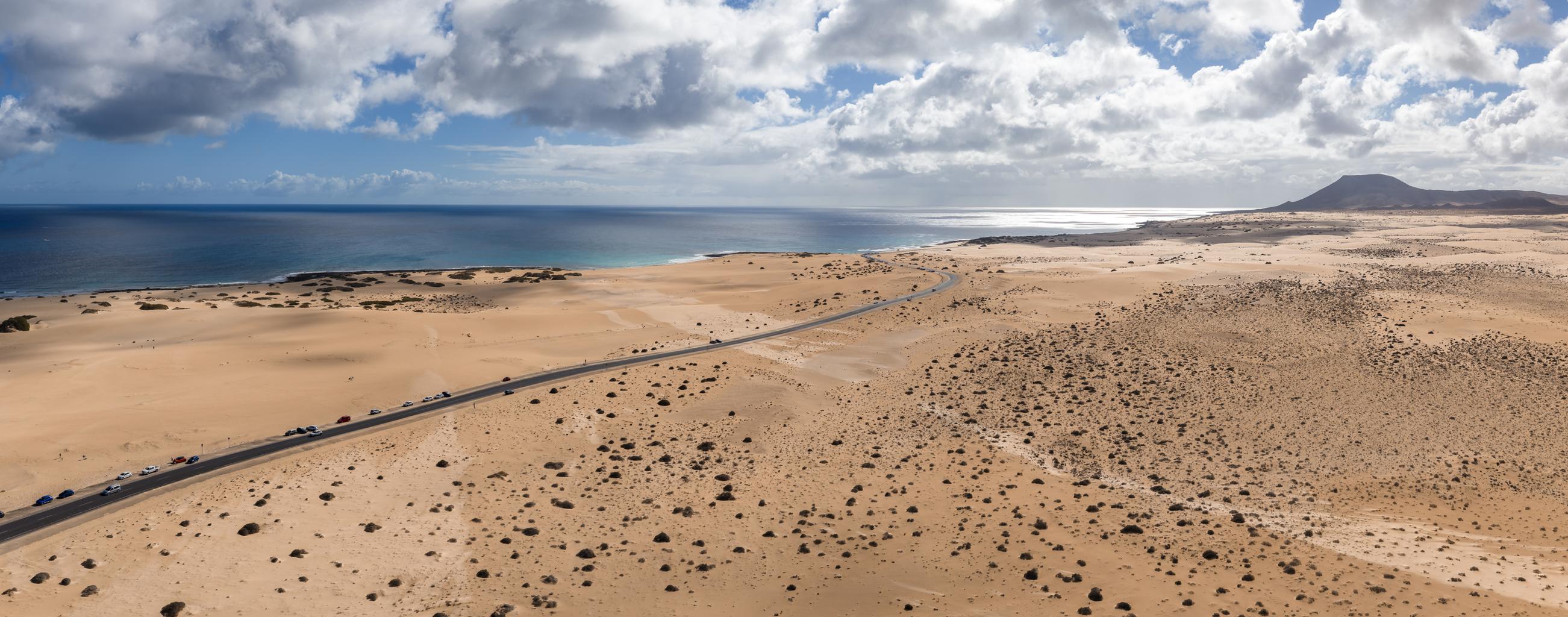 The vast Corralejo sand dunes stretching toward the ocean with a road cutting through