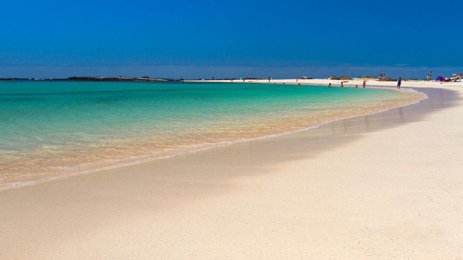 Playa de La Concha in El Cotillo with crystal-clear turquoise water and white sand curving along the sheltered lagoon