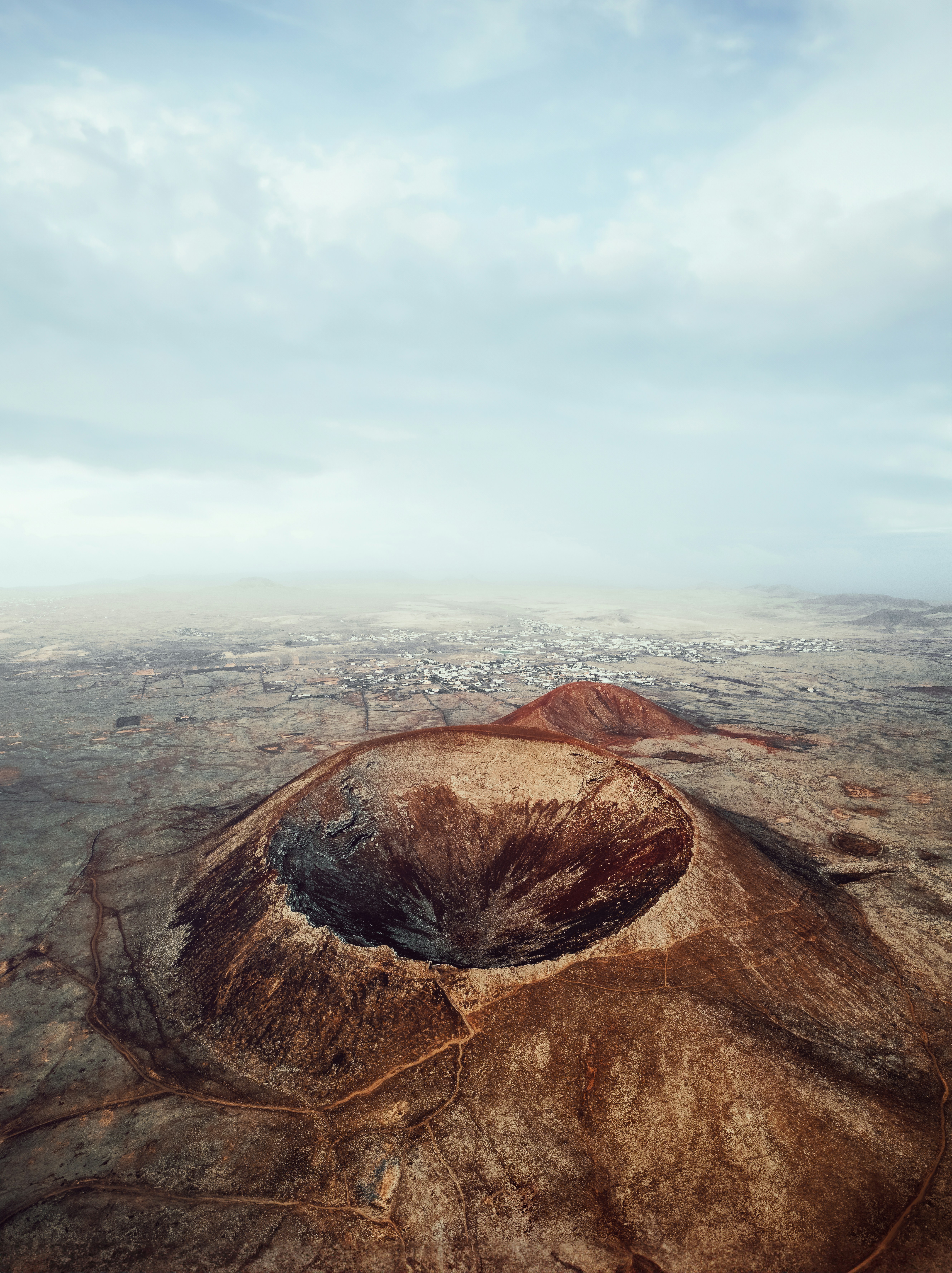 Aerial view looking into the deep bowl of a volcanic crater on the barren Fuerteventura plains